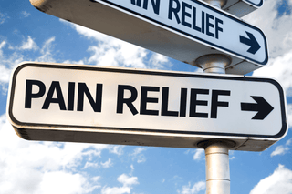Sign pointing towards pain relief for joint health, muscle relaxation, and headache relief against a blue sky background.
