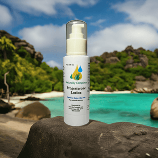 Natural Progesterone Lotion bottle on a rock near a tropical beach, highlighting soy-free and non-GMO features.