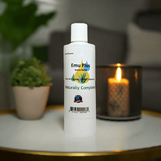 Emu Plus Menthol-Capsicum Pain Relief Bottle with Candle and Plant Background, Soy-Free, Non-GMO, Plant-Based.