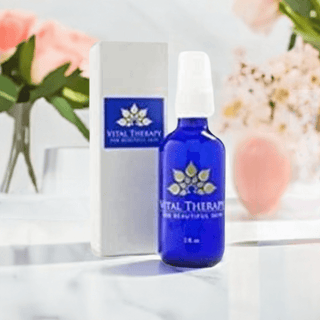 Vital Therapy Blemish Rescue 1 oz. bottle on marble surface with flowers, soy-free skincare for blemish relief and anti-inflammatory benefits.