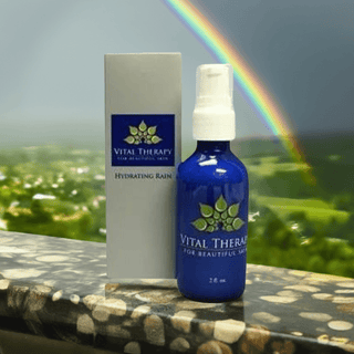 Hydrating Rain facial moisturizer 2 oz. bottle with packaging, featuring a rainbow background, skincare product made in the USA.