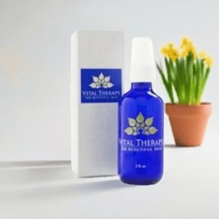 Blue bottle of Healing Cream with box, skincare product in front of potted yellow flowers, 2 oz, made in the USA.