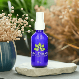 Blue Vital Therapy peptide facial lotion bottle, 2 oz, on a stone surface with plants, promoting skincare for beautiful skin.