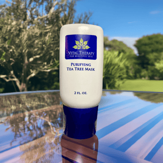 Purifying Tea Tree Mask 2 oz bottle on outdoor table, plant-based and soy-free skincare product made in the USA.